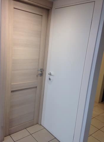 Porta interna in rovere chiaro affiancata a una porta laccata bianca